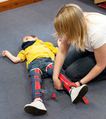 A carer attaches splints to a boy's
                  legs