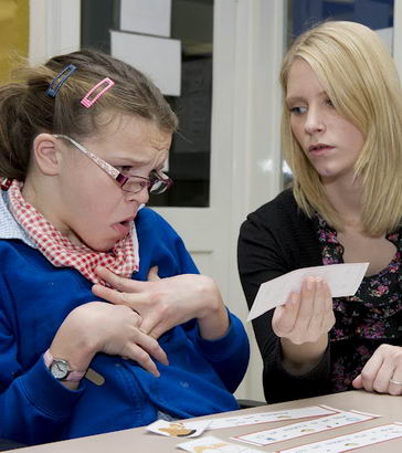 Teacher helps disabled girl to
                  recognise cards.