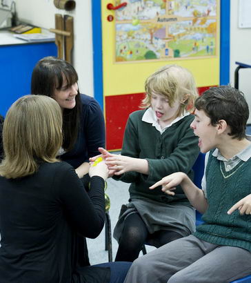 Two teachers discussing with
                  disabled students.