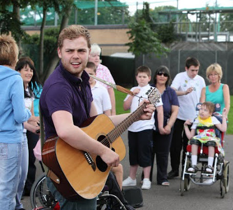 Teacher playing the guitar in front of
                  children