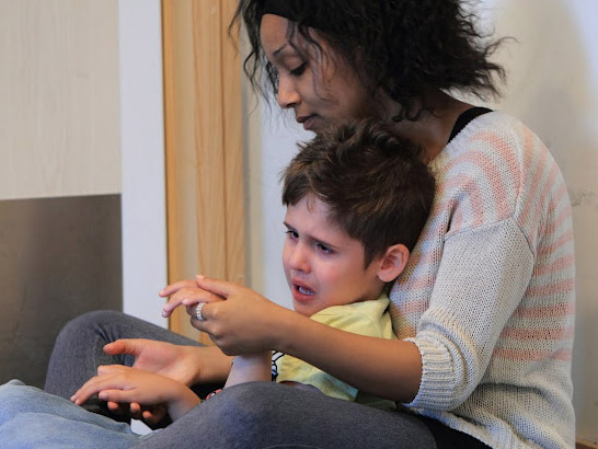 Carer comforts a distressed boy.