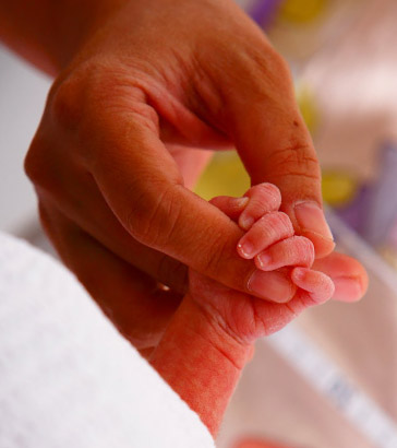 Newborn grasping mother's
                  finger.