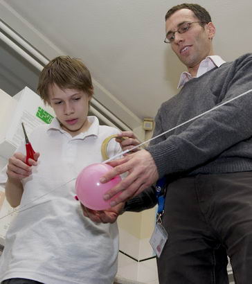 A science teacher helps a boy
                  with an experiment