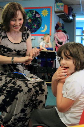 A girl sitting opposite her teacher turns
                  to smile at the camera