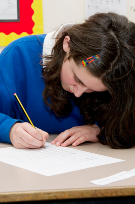 A girl writes on a sheet of paper