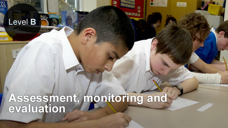 A row of boys writing at a classroom table