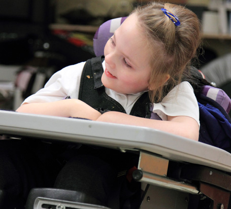 A girl in a specialist chair smiles
