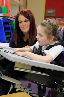 A teacher prompts a girl to trigger a switch which activates a PC screen presentation