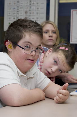 A boy and a girl in front of a keyboard with their teacher
