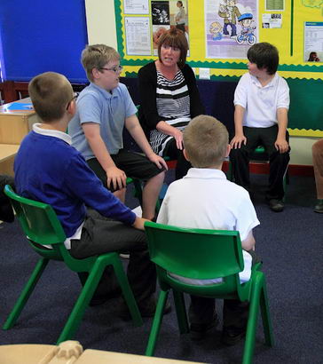 A group of students and two teachers sit in a circle