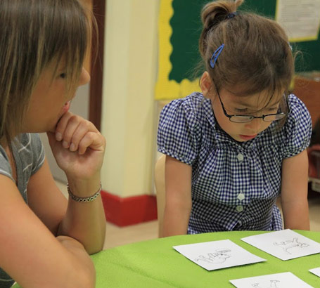 A girl looks at four picture cards