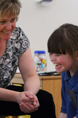 A girl laughing with her teacher