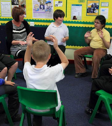 A group of children talk to one another in a circle